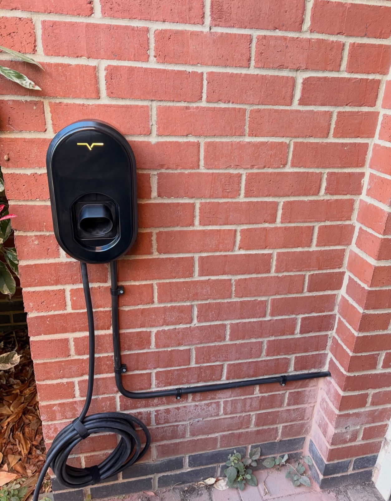 Socketed EV charger installed on a red brick exterior wall